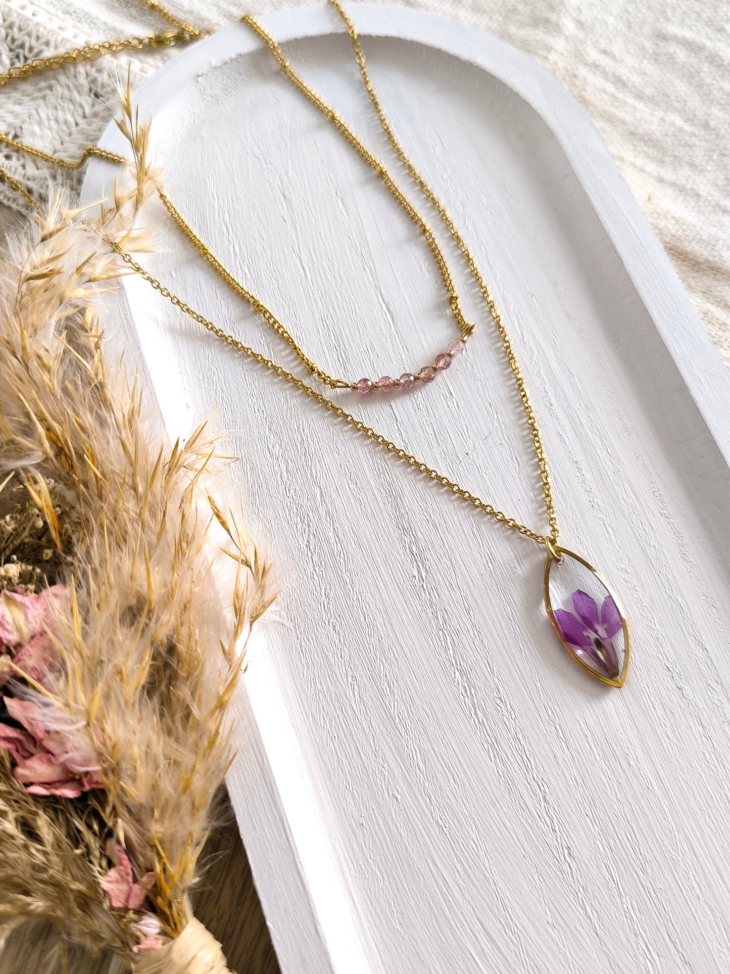 Duo de colliers composés de pierre de quartz fraise, d'une fleur séchée de lobélie et d'acier doré.