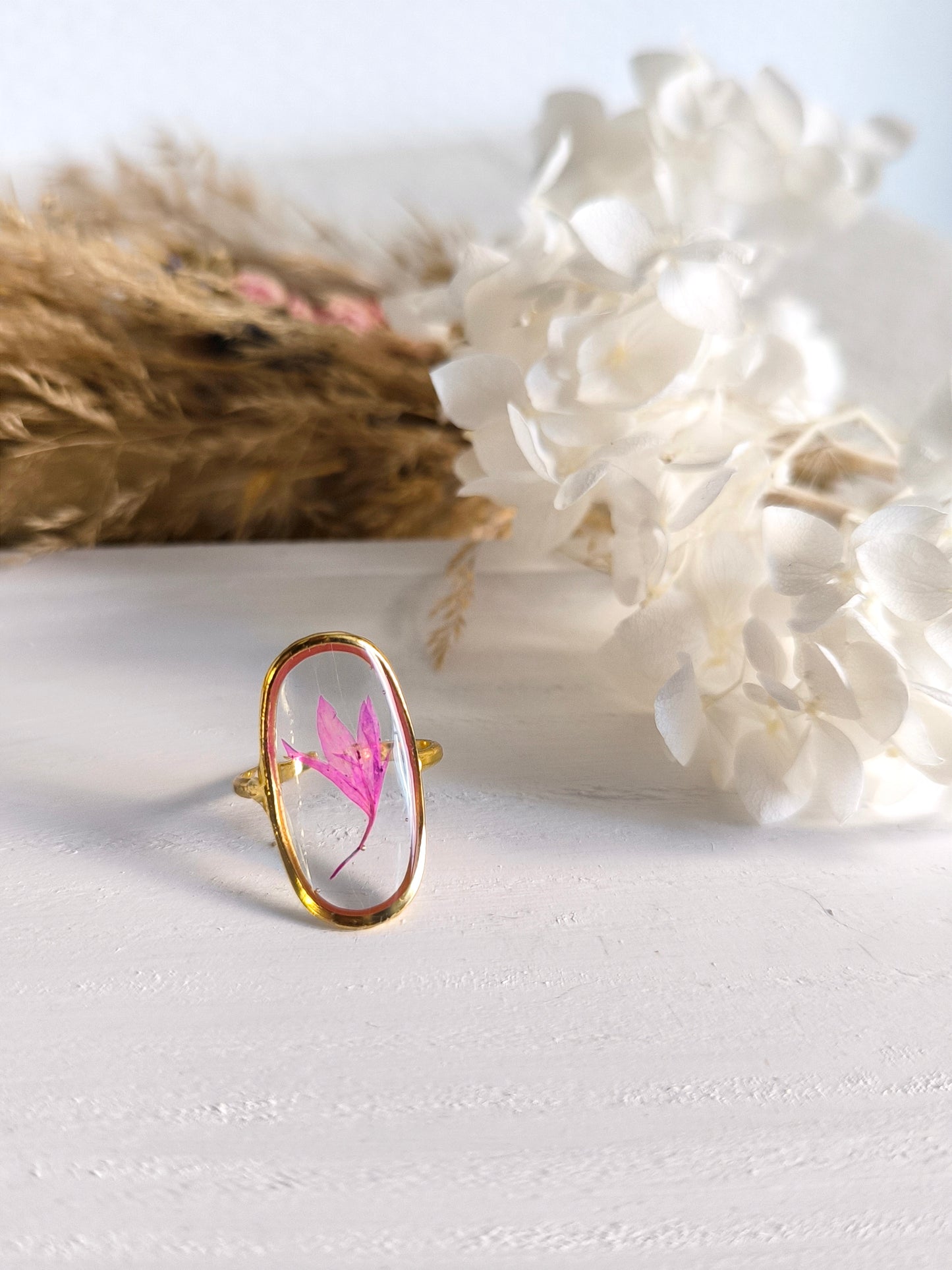 Bagues en acier doré avec fleurs séchée encapsulée dans une résine transparente.