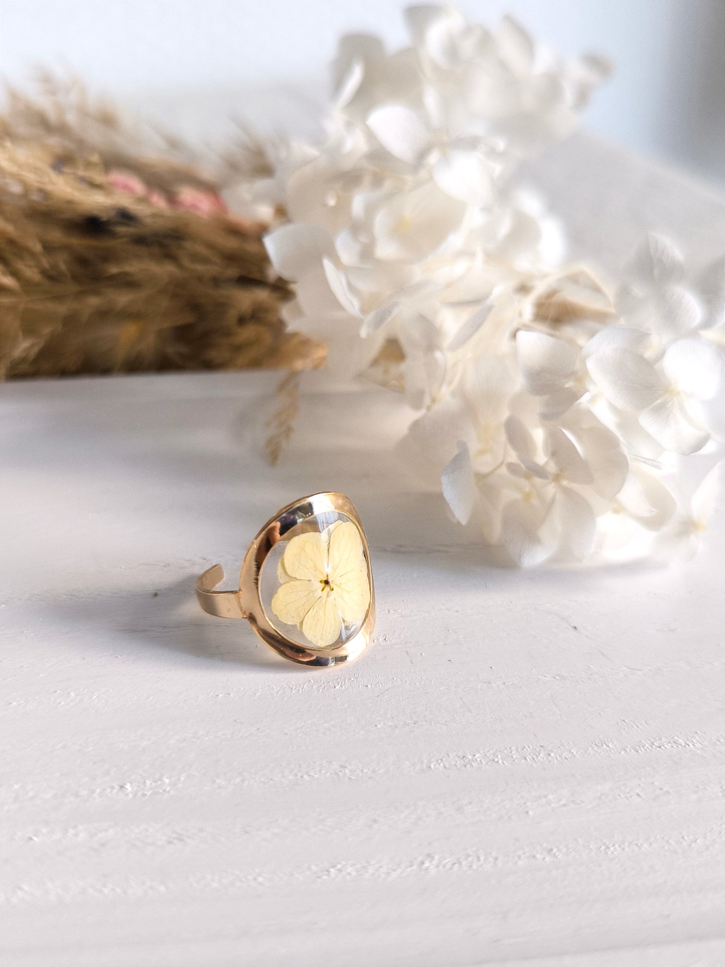 Bagues en acier doré avec fleurs séchée encapsulée dans une résine transparente.