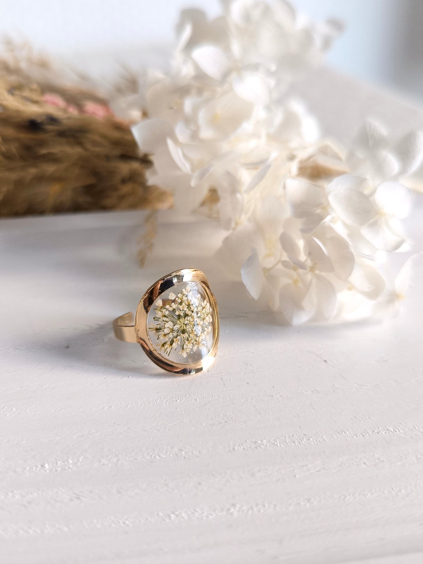 Bagues en acier doré avec fleurs séchée encapsulée dans une résine transparente.