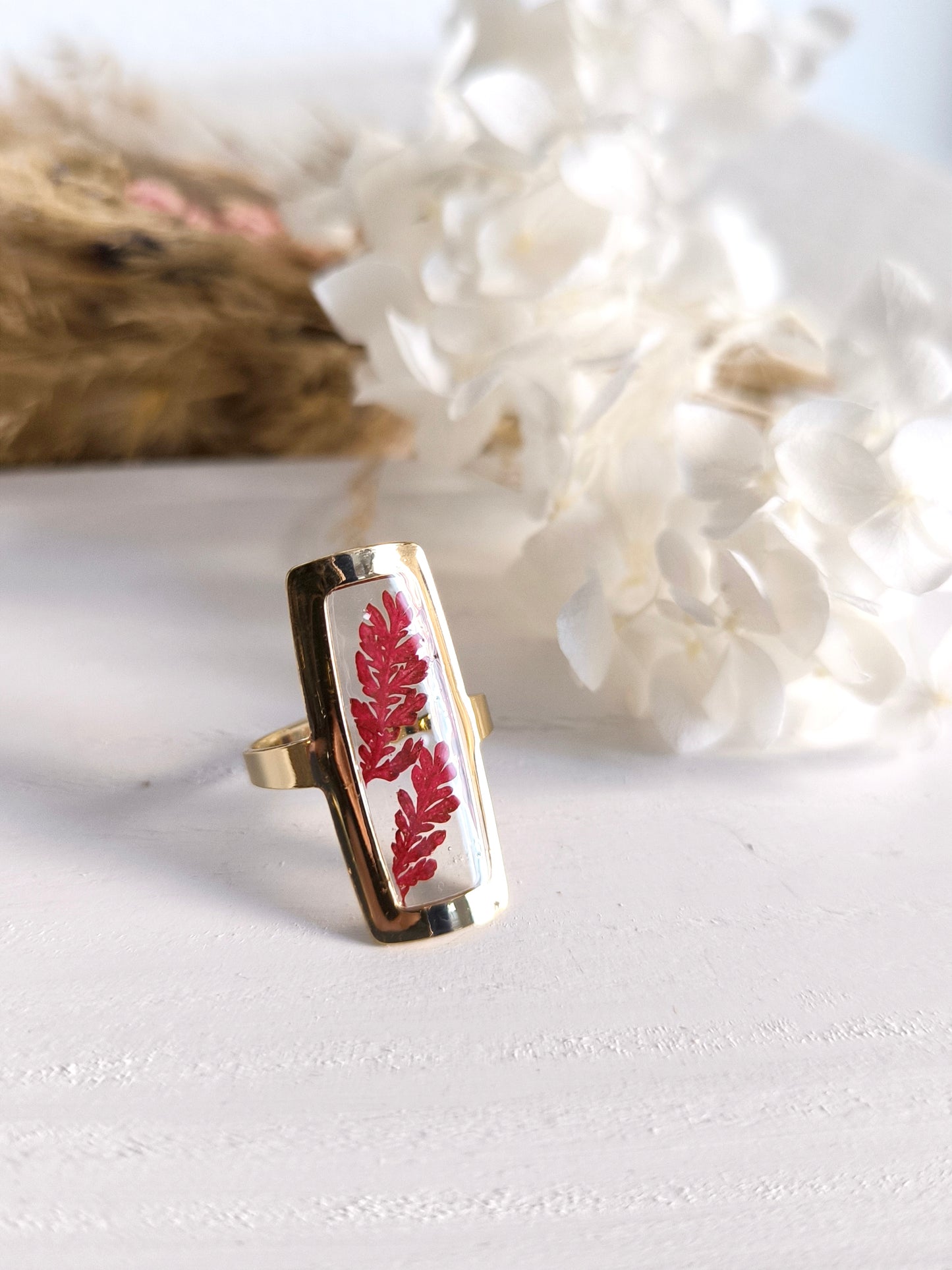 Bagues en acier doré avec fleurs séchée encapsulée dans une résine transparente.