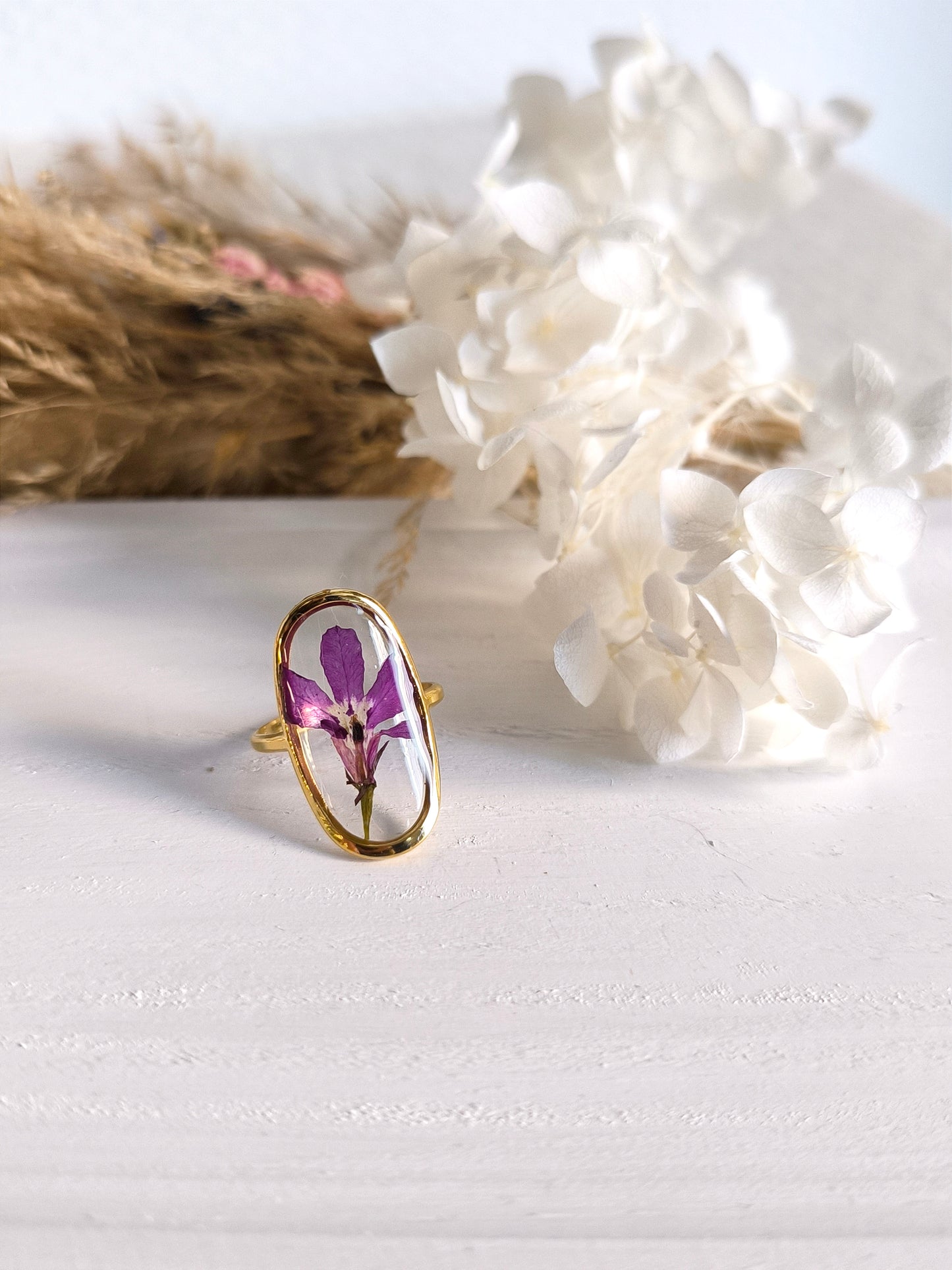 Bagues en acier doré avec fleurs séchée encapsulée dans une résine transparente.