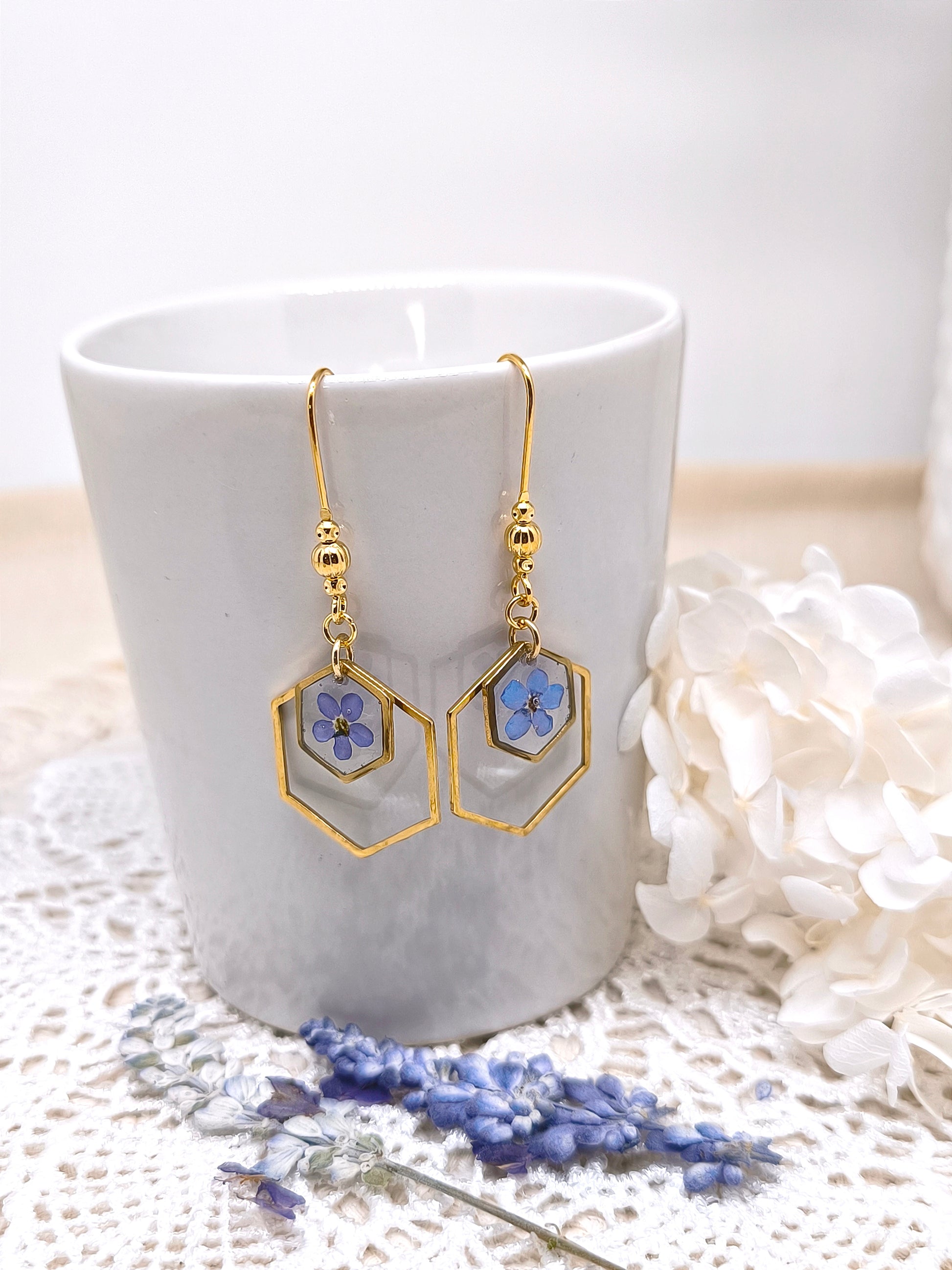 Boucles d'oreilles géométriques avec fleurs de myosotis et résine transparente.