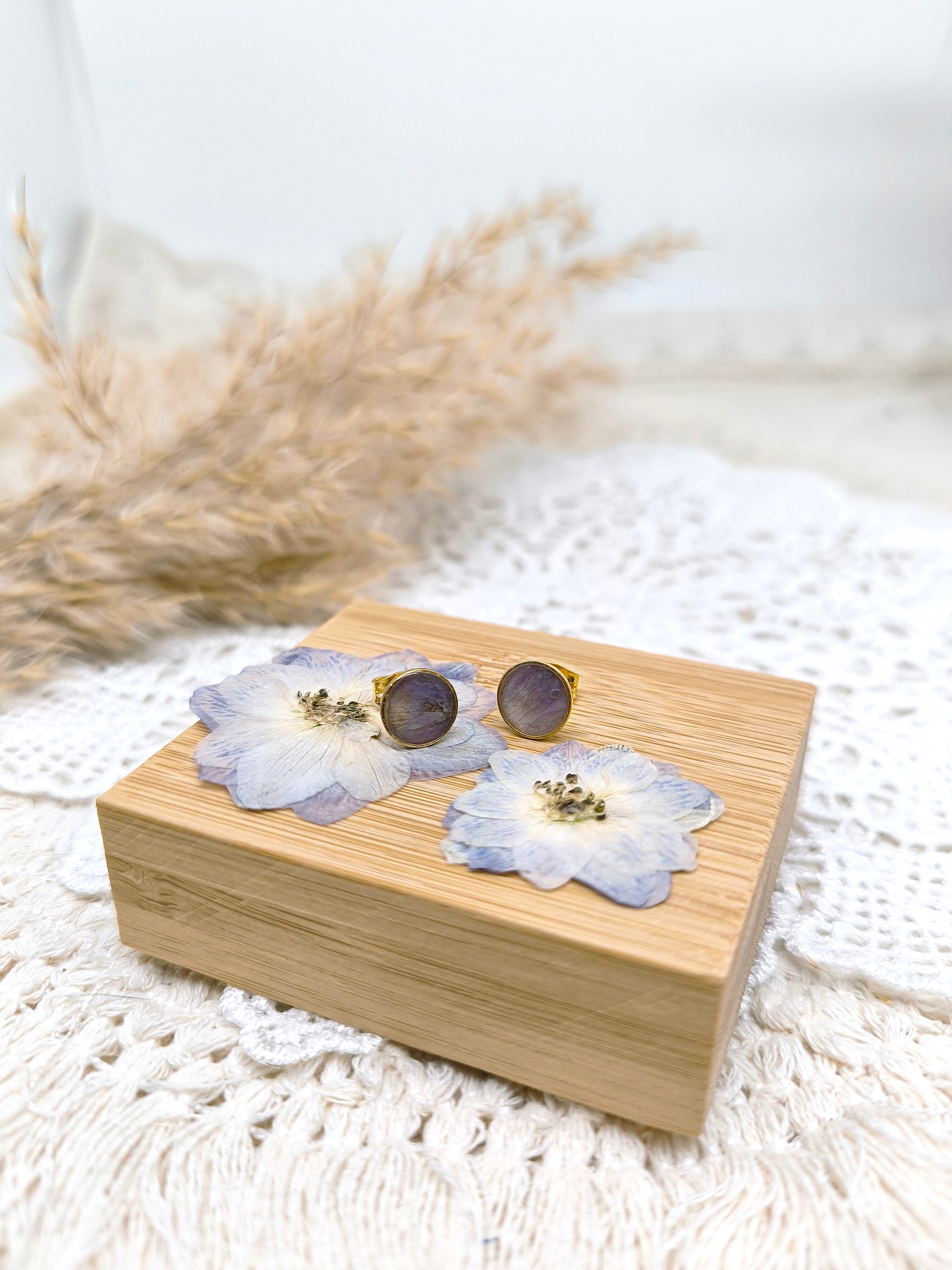 boucles d'oreilles en forme de puces, fleur de delphinium et résine transparente.