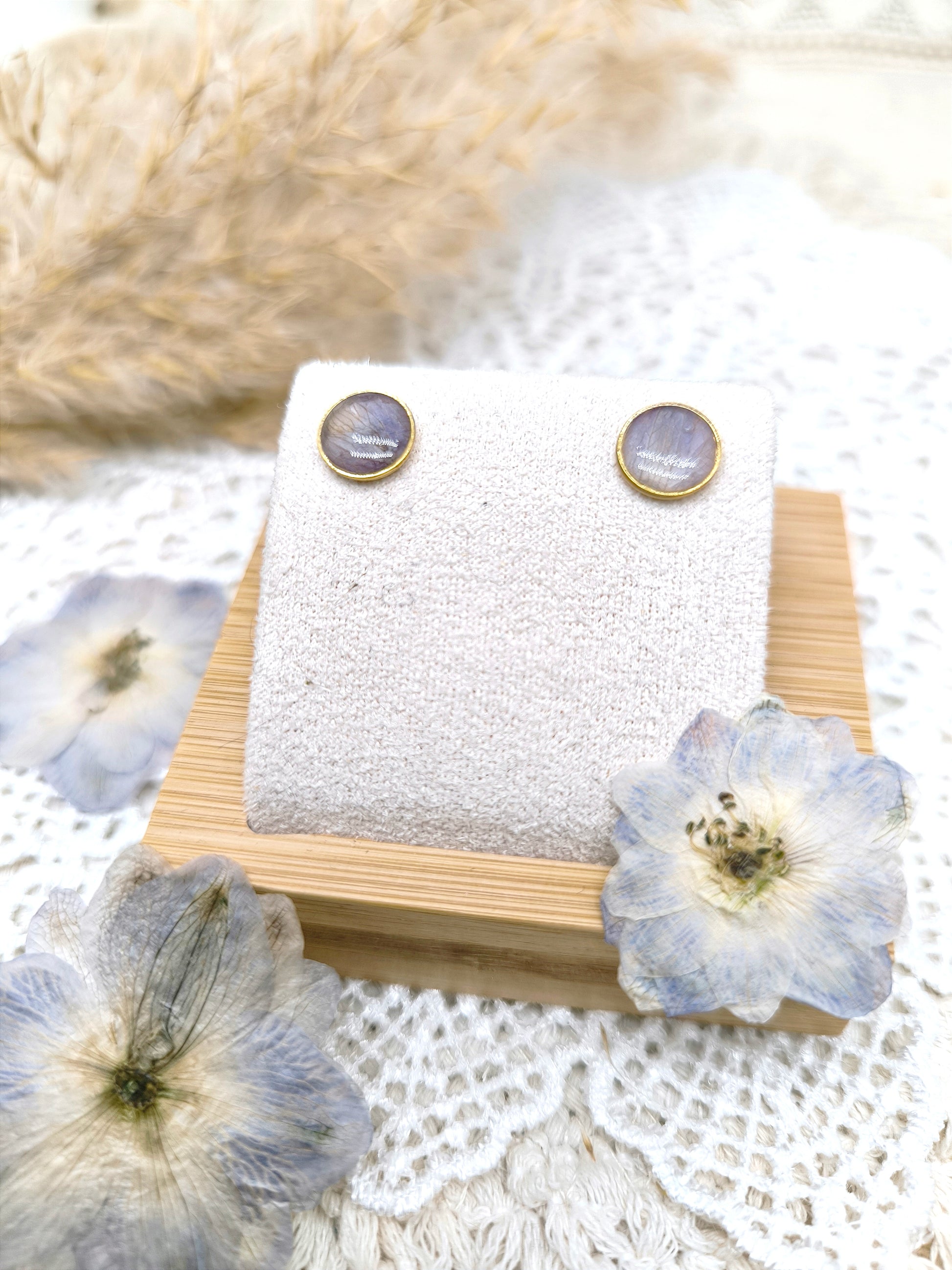 boucles d'oreilles en forme de puces, fleur de delphinium et résine transparente.