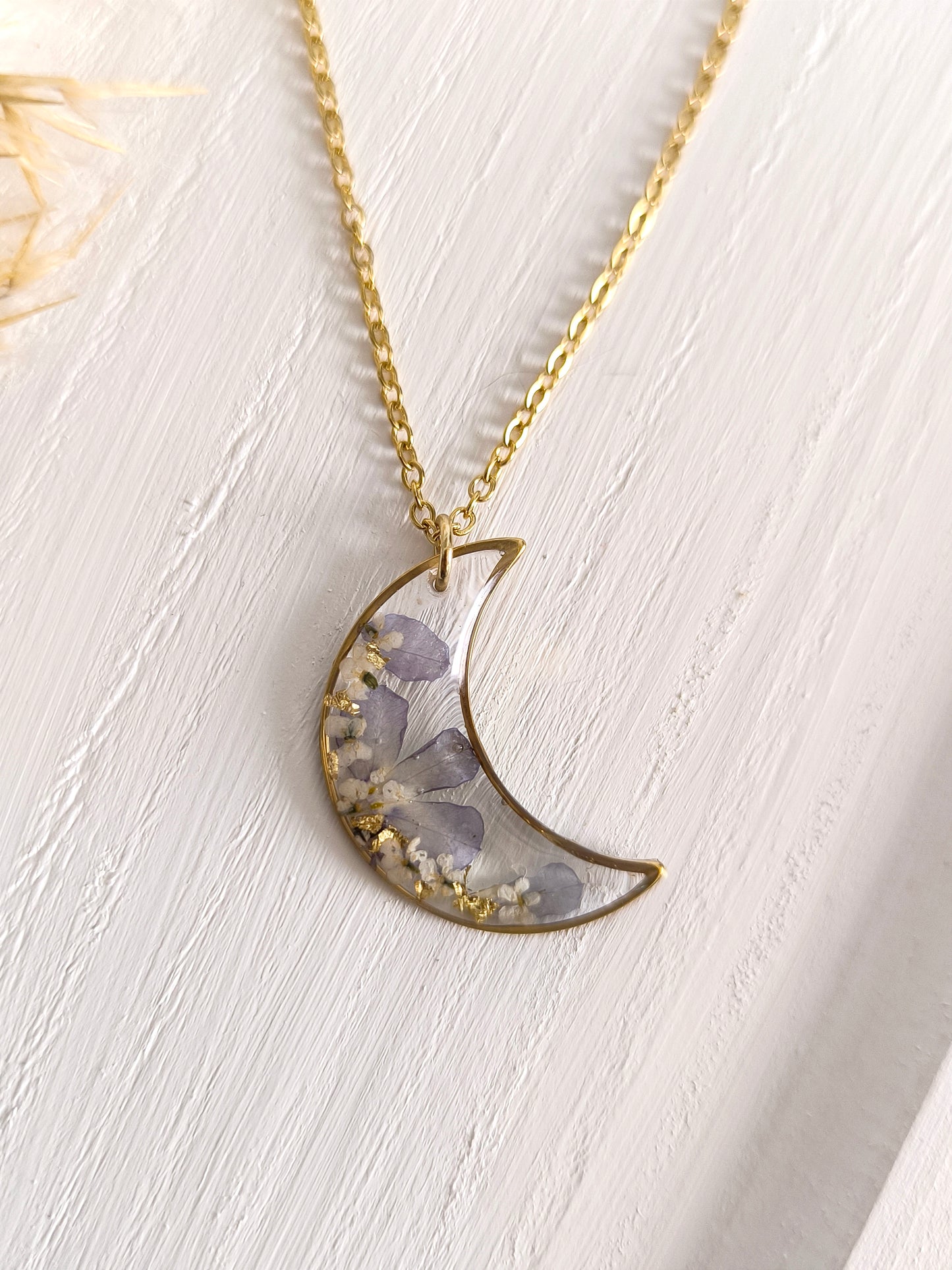 Collier médaillon lune rempli de fleurs séchées glacées dans une résine transparente. 