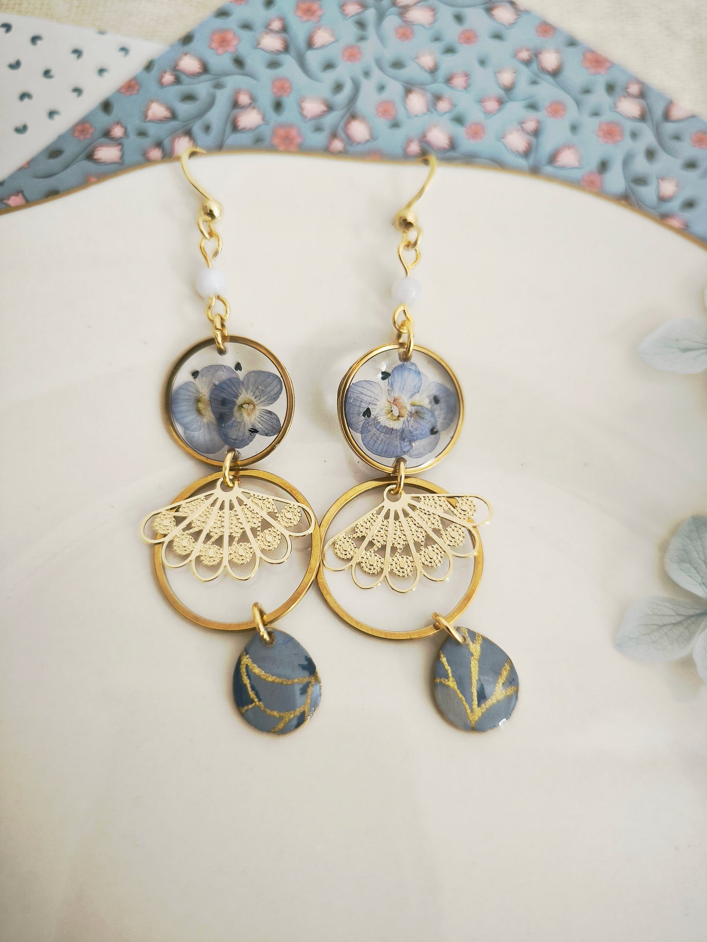 Boucles d’oreilles florales en résine – fleurs bleues & acier doré